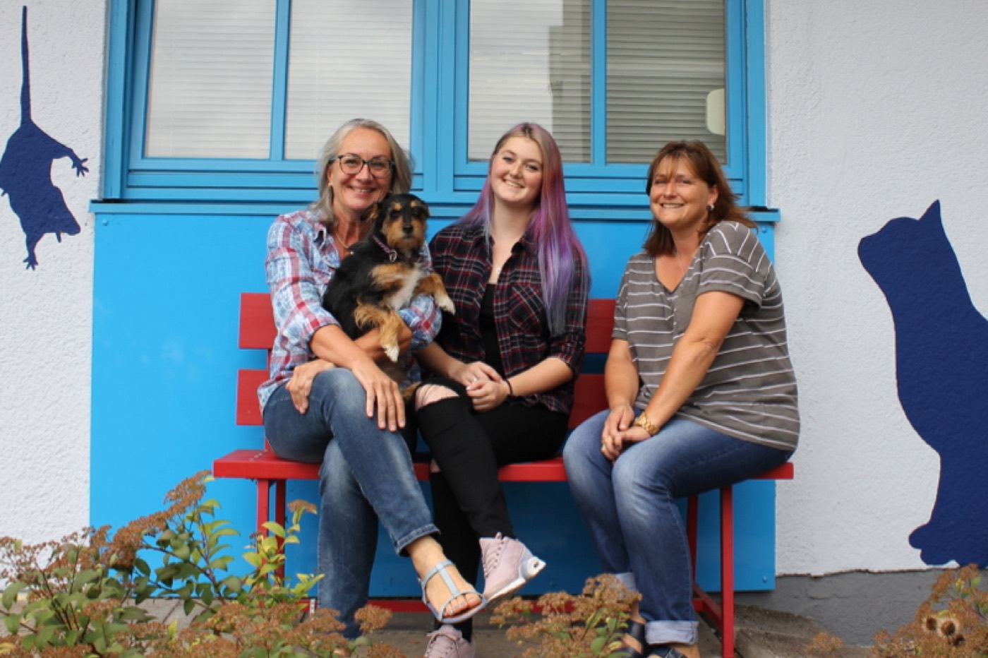 Dr. Ulrike Neuhaus mit ihren Tierarzthelferinnen Larissa Gallecker und Sylvia Petermeier auf einer roten Bank vor der Praxis in Dachau